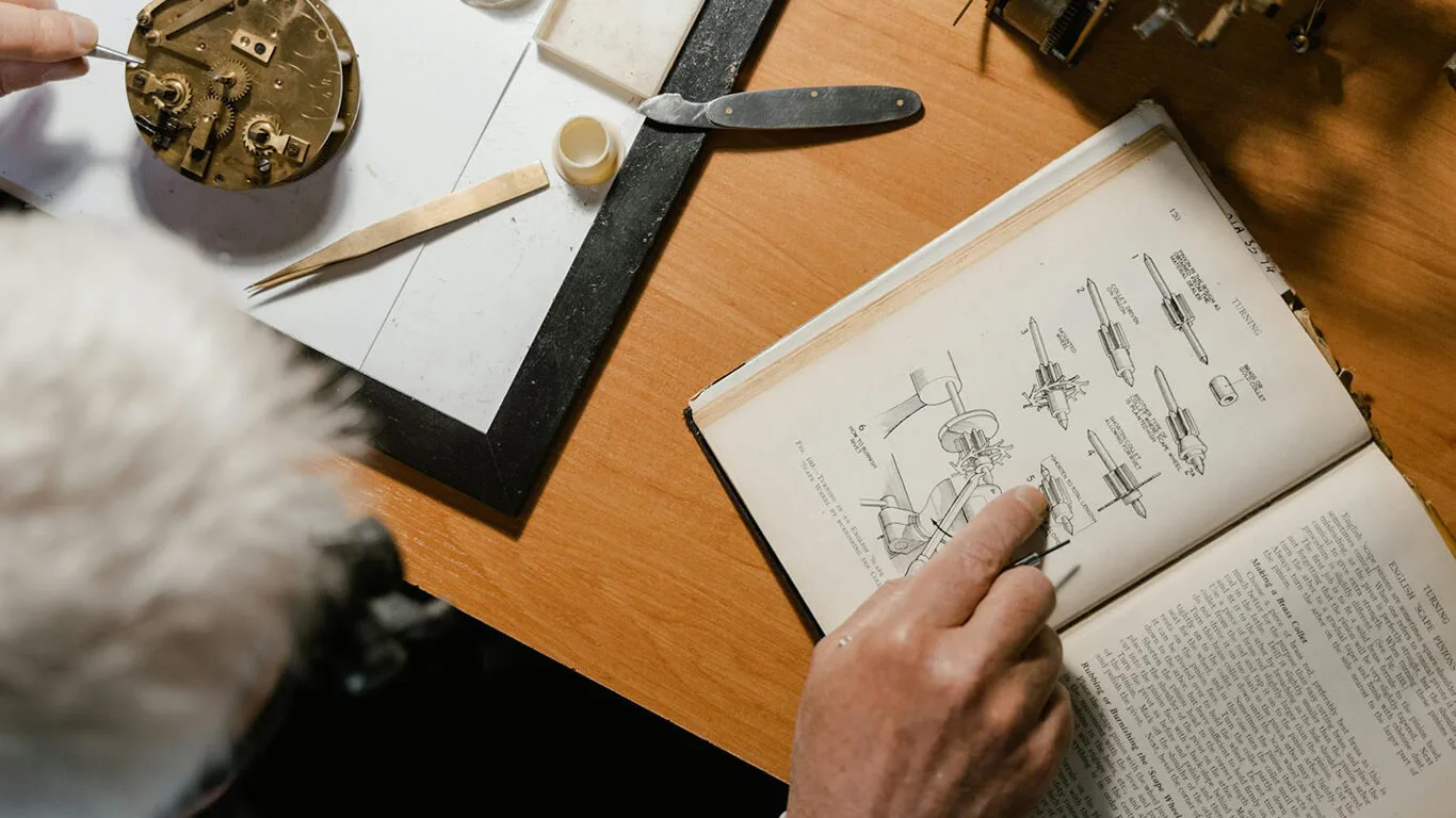 image shows man reading documentation illustration for repairing a watch