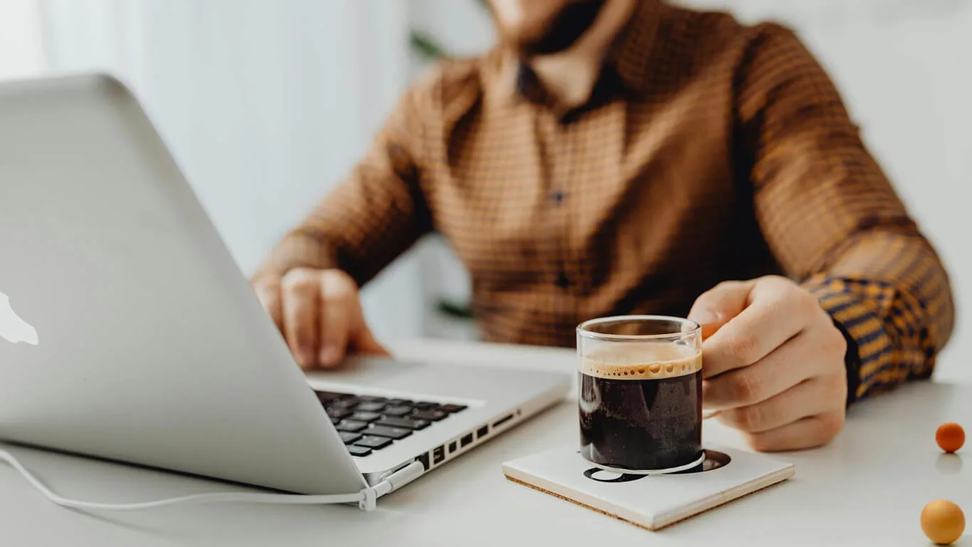 image shows man drinking coffee and working online with documentation